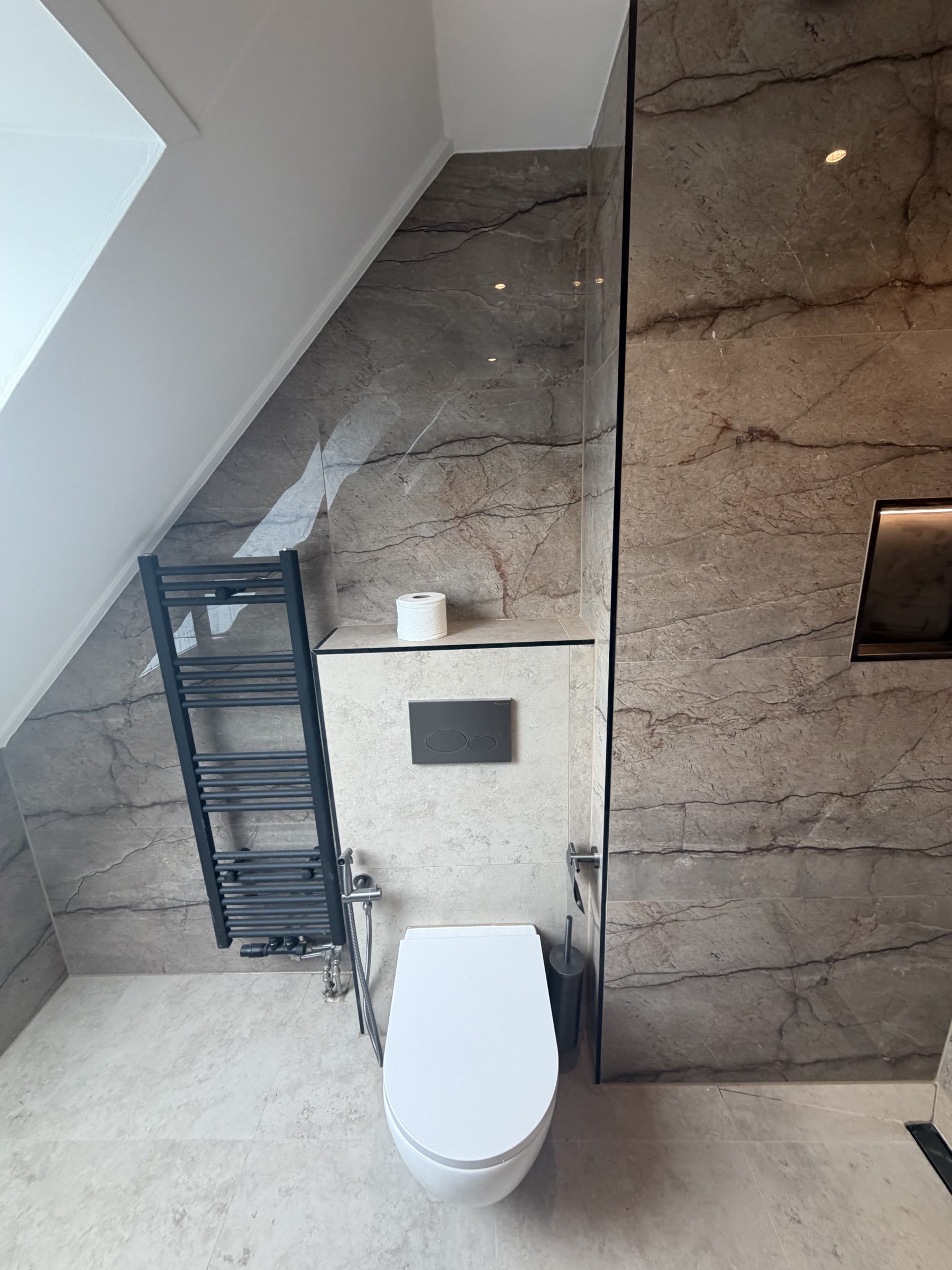 Hangtoilet met marmerlook tegels en zwarte radiator