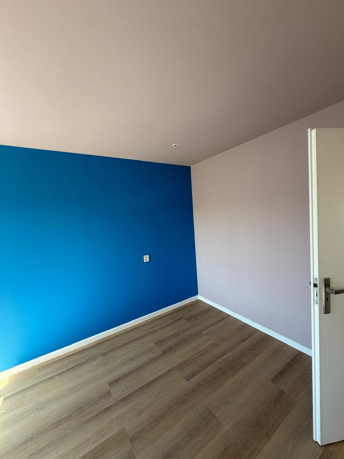Kamer met blauwe accentmuur en laminaat