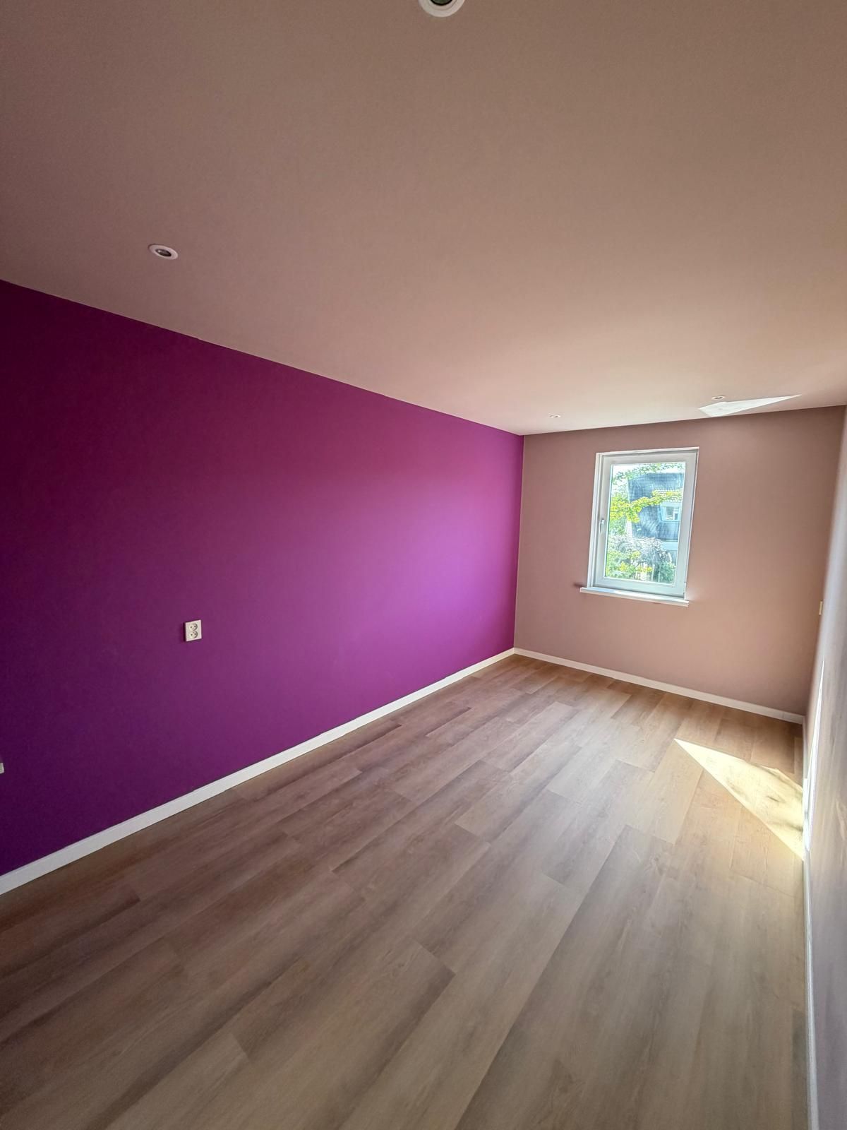 Kamer met paarse accentmuur en laminaat